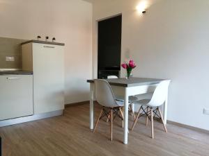 mesa de comedor con sillas blancas y cocina en Apartment Annive en Levico Terme