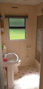 La salle de bains est pourvue d'un lavabo, de toilettes et d'une fenêtre. dans l'établissement Na Piaskach Domek na Roztoczu, à Narol