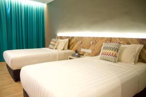 two beds in a hotel room with green curtains at G5 HOTEL AND SERVICED APARTMENT in Johor Bahru