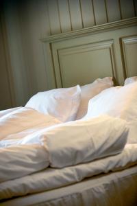 an unmade bed with white sheets and pillows at Krokstad Herrgård in Säffle