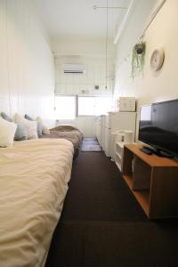 Una habitación con tres camas y un televisor de pantalla plana. en Azami 7 Miyakojima, en Isla Miyako