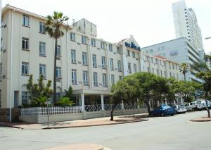 a large white building with palm trees in front of a street at The Balmoral in Durban