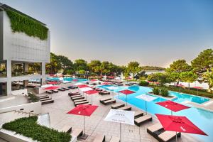an outdoor pool with red umbrellas and lounge chairs at Hotel Parentium Plava Laguna in Poreč