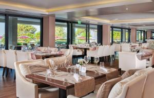 a restaurant with tables and white chairs and windows at Hotel Parentium Plava Laguna in Poreč
