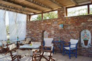 a patio with tables and chairs and a brick wall at Sevasti Rooms in Platis Gialos