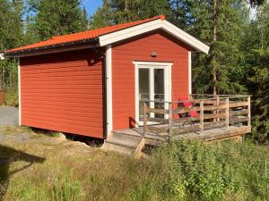 un abri rouge avec une terrasse couverte dans un champ dans l'établissement Fjällstuga, à Idre