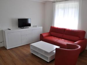 ein Wohnzimmer mit einem roten Sofa und einem TV in der Unterkunft Ferien-und Gästehaus Wilma in Langenargen