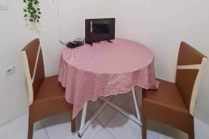 einen rosa Tisch mit einem Fernseher darüber in der Unterkunft Pesona Wisata Alam Ciparay Endah Mitra RedDoorz in Bogor