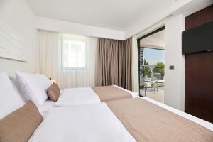 a hotel room with a large bed and a television at Hotel Parentium Plava Laguna in Poreč