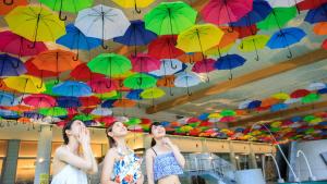 Tres chicas están mirando paraguas coloridos en Kinugawa Hotel Mikazuki, en Nikko