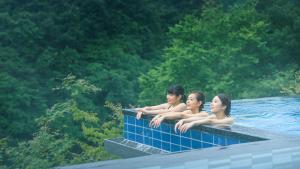 tres chicas sentadas en el borde de una piscina en Kinugawa Hotel Mikazuki en Nikko