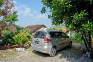 een kleine zilveren auto geparkeerd naast een boom bij RedDoorz @ Jalan Raya Kaliwungu Selatan Kendal in Kendal