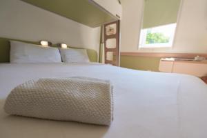 a bed with a white comforter and pillows at Ibis Budget Avignon Nord in Le Pontet