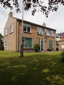 een stenen huis met een paal in de tuin bij de Pastorie in Hollum