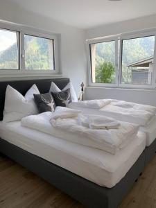 Cette chambre comprend un grand lit blanc et des fenêtres. dans l'établissement Bellevue Apartments, à Bürserberg