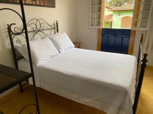 ein Bett mit weißen Laken und Kissen in einem Schlafzimmer in der Unterkunft Casa de hospedagem Mimos de Minas 2 in Tiradentes