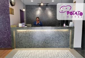 a woman standing behind the counter of a koala hotel at Potato Hotel in Taiping