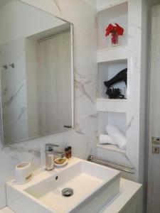 a white bathroom with a sink and a mirror at Bouganville Bed & Breakfast Stegna in Archangelos