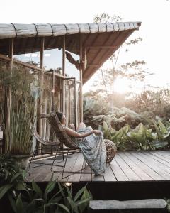 a woman sitting in a hammock on a porch at Hideout Falcon in Selat