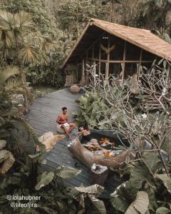 two people sitting on a wooden walkway in front of a house at Hideout Falcon in Selat