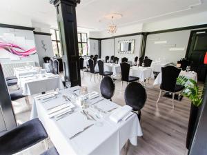 a dining room with white tables and black chairs at Verve Hotel in Bedford