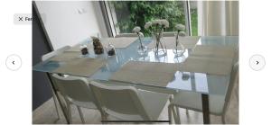 una mesa de comedor de cristal con sillas blancas y flores. en Villa moderne avec piscine, front de mer en Casablanca