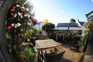a patio with a wooden table and flowers at Victoria Inn in Penzance