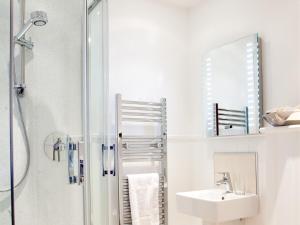 a white bathroom with a shower and a sink at The Victoria Inn in Truro