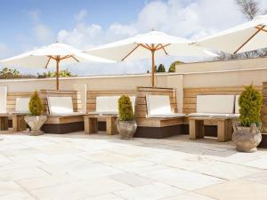 a patio with white umbrellas and benches at The Victoria Inn in Truro