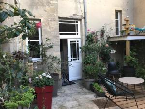 a patio with a white door and lots of plants at B&B Nathalie in Bayeux
