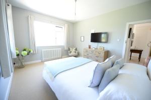 a white bedroom with two beds and a television at Pinkmead Estate and Vineyard in Osborne