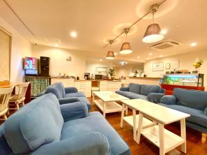 uma sala de estar com sofás azuis e uma cozinha em ホテルサンドリバー石垣島 em Ishigaki Island