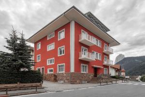 un edificio rosso con finestre bianche sul lato di Casa al Sole a Ortisei