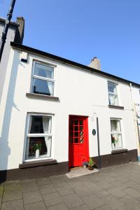 Casa blanca con puerta roja y ventanas en Village Cottage Bushmills, en Bushmills