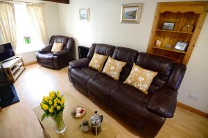 a living room with a brown leather couch and chairs at Village Cottage Bushmills in Bushmills