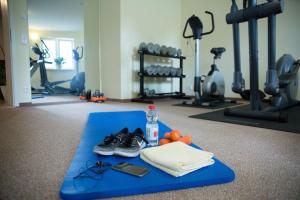 einen Fitnessraum mit einer blauen Matte mit Schuhen und einer Flasche Wasser in der Unterkunft Pension Villa-Ingeborg in Fürstenberg-Havel
