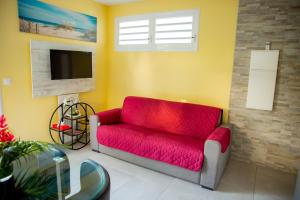 a living room with a red couch and a tv at Villas Ixora in Sainte-Anne