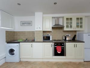 a kitchen with white cabinets and a stove top oven at Vine Studio in Leeds