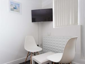 a living room with two white chairs and a tv at Vine Studio in Leeds