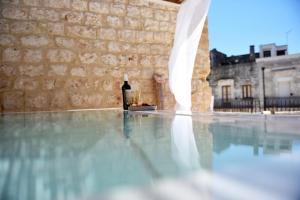 una bottiglia di vino seduta sul pavimento della piscina di Arya Nobile Dimora By Raro Villas a Carovigno