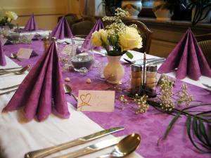 uma mesa com pano de mesa roxo com flores e guardanapos em Pension Waldesruh em Welschneudorf