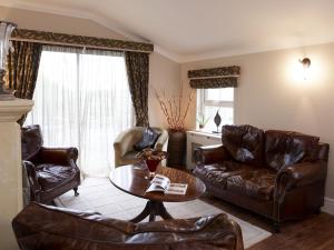 a living room with leather furniture and a table at Wall Hill Farm in Northwich