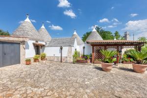 a large white house with potted plants in a driveway at Villa Trulli Natura by BarbarHouse in Noci