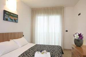 a bedroom with a bed and a vase with flowers on it at Residence A-More in Rimini