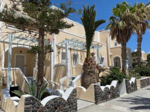 a house with palm trees and chairs in front of it at Dioskouri Art Villas in Kamari