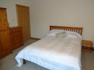 1 dormitorio con cama blanca y tocador de madera en Wester Muirhouse, en Linlithgow