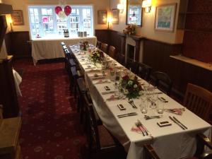 a long table in a restaurant with white tables and chairs at The Wheatsheaf Inn in Cuckfield