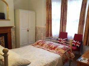 a bedroom with a bed and two red chairs at White Guest House in Bath