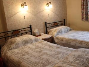 1 dormitorio con 2 camas y 2 luces en la pared en White Guest House, en Bath