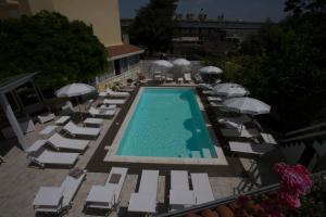 einen Blick über einen Pool mit Stühlen und Sonnenschirmen in der Unterkunft Hotel Villa Serena in Castellammare di Stabia